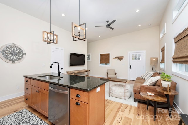 kitchen featuring sink, decorative light fixtures, dark stone countertops, dishwasher, and a kitchen island with sink