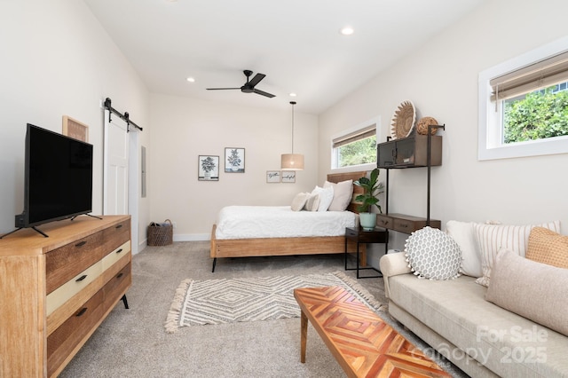 carpeted bedroom with a barn door and ceiling fan