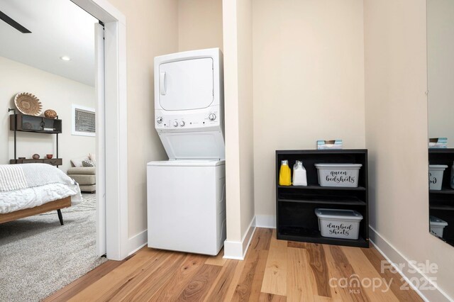 clothes washing area featuring stacked washer and dryer and hardwood / wood-style floors