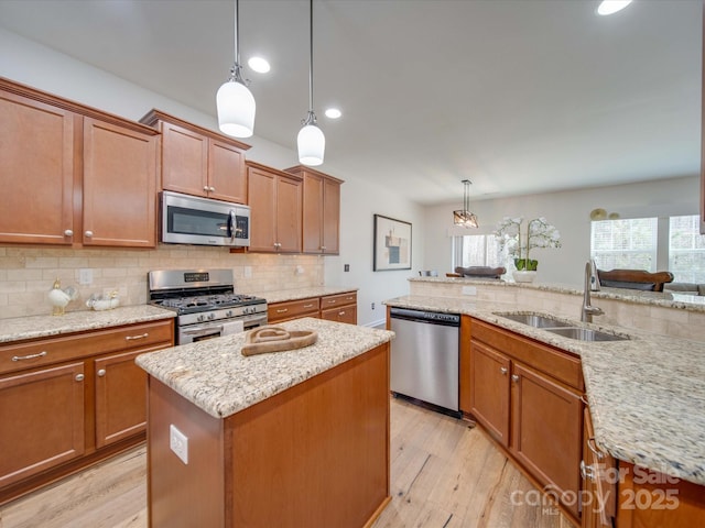 kitchen featuring sink, appliances with stainless steel finishes, backsplash, a kitchen island, and decorative light fixtures