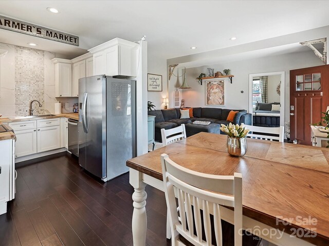 kitchen featuring appliances with stainless steel finishes, sink, white cabinets, decorative backsplash, and dark wood-type flooring