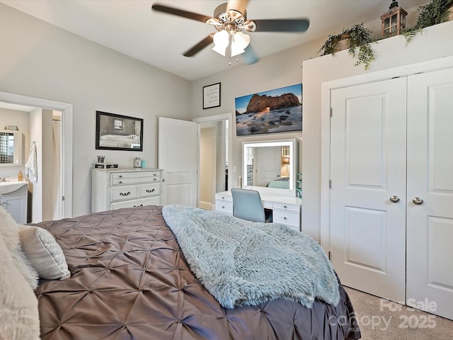 bedroom with connected bathroom, built in desk, sink, ceiling fan, and a closet