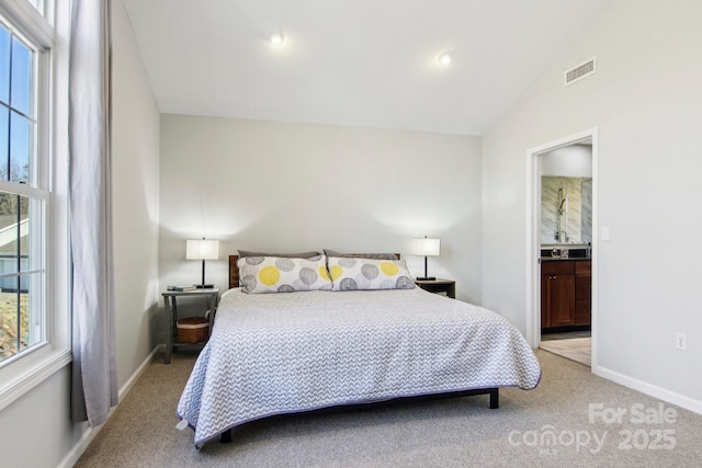 carpeted bedroom with multiple windows, lofted ceiling, and ensuite bath