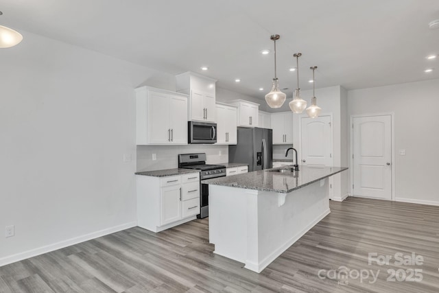 kitchen featuring pendant lighting, sink, appliances with stainless steel finishes, a kitchen island with sink, and white cabinetry