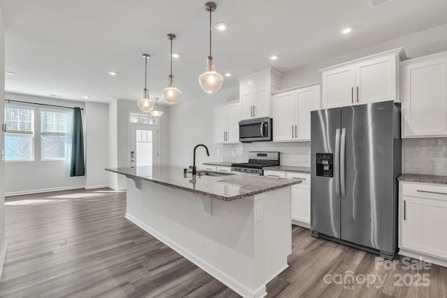 kitchen with appliances with stainless steel finishes, sink, a center island with sink, and white cabinets