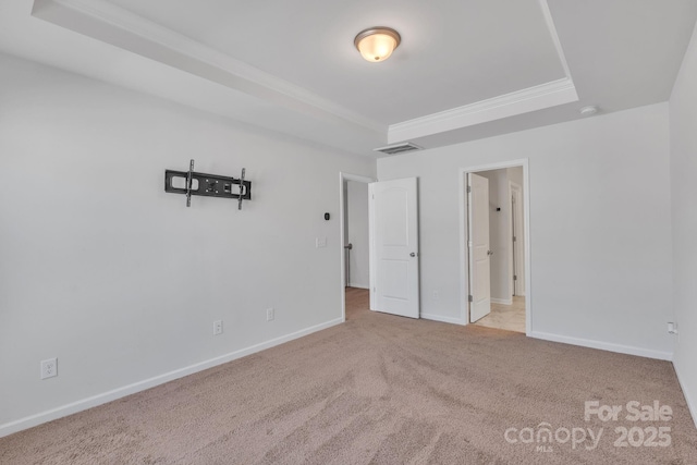 unfurnished bedroom featuring crown molding, light carpet, and a tray ceiling