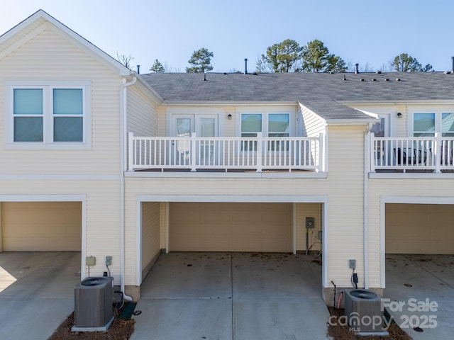 back of property featuring a garage, a balcony, and central air condition unit