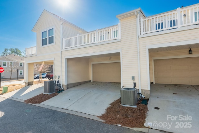 view of front facade with central AC unit, a garage, and a balcony