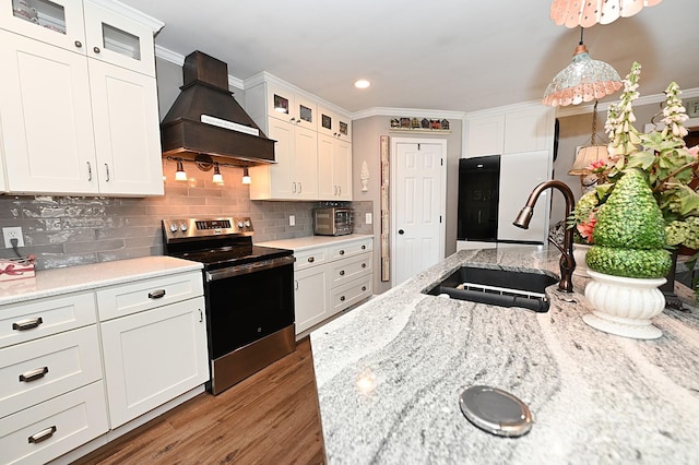 kitchen featuring custom exhaust hood, hanging light fixtures, white cabinets, and electric stove