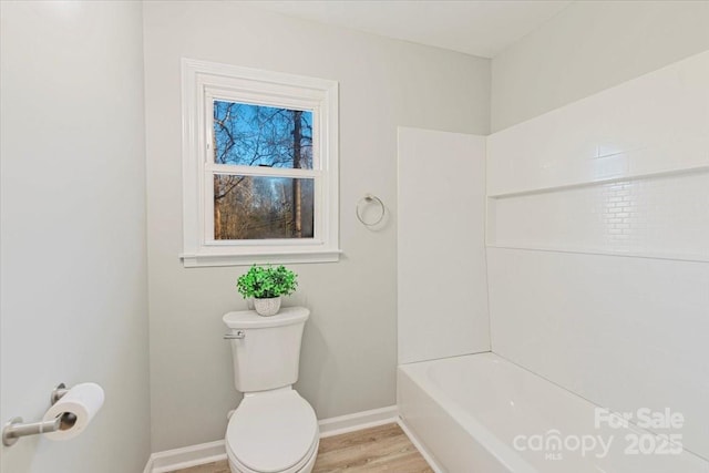 bathroom featuring wood-type flooring, shower / washtub combination, and toilet