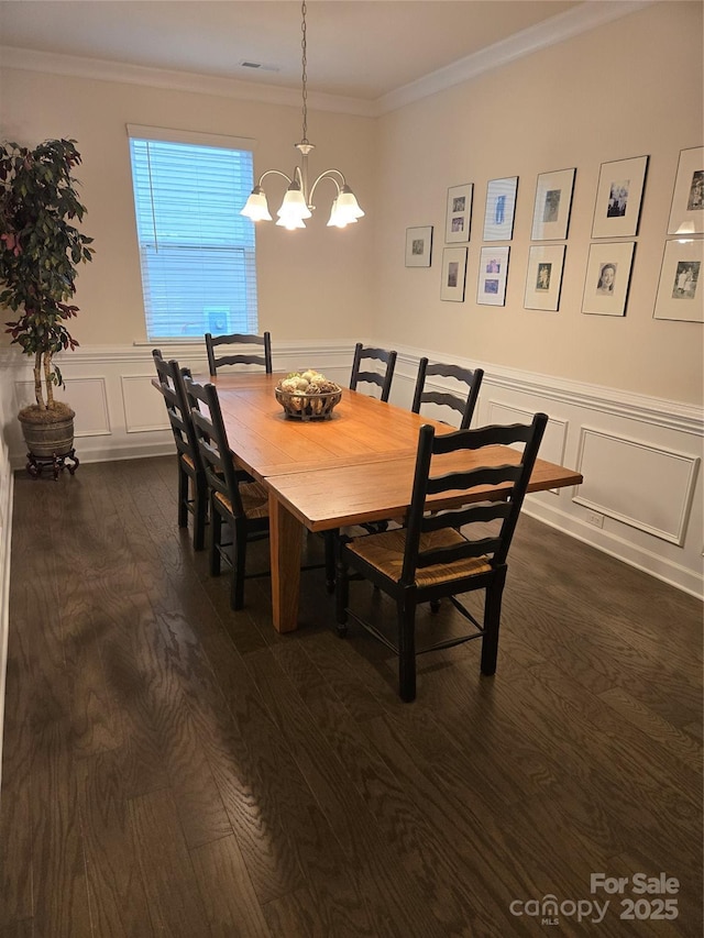 dining area featuring ornamental molding, dark wood-style flooring, a notable chandelier, and a decorative wall