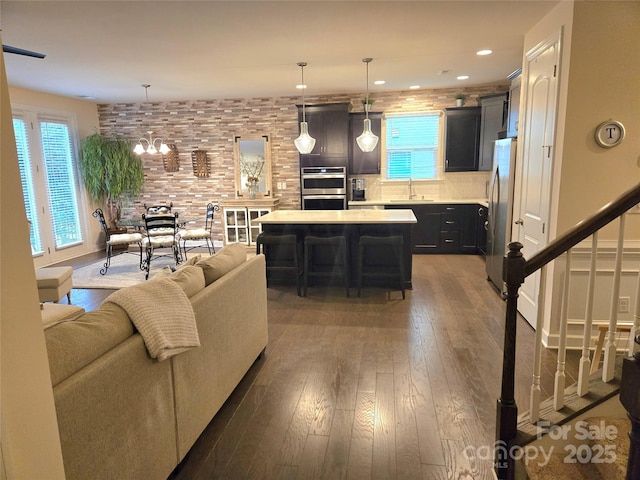 living room featuring dark wood-type flooring, recessed lighting, a chandelier, and stairs