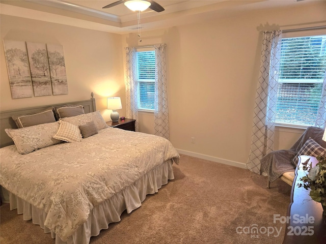 carpeted bedroom with a ceiling fan, a tray ceiling, and baseboards