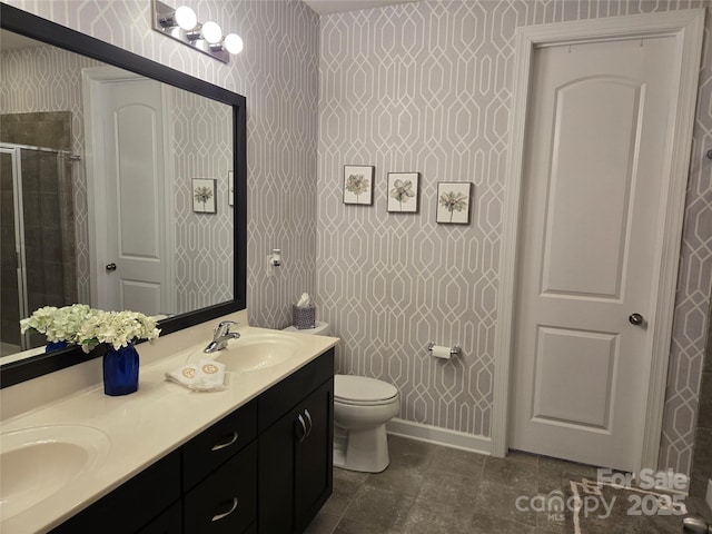 full bathroom with double vanity, wallpapered walls, a sink, and a stall shower