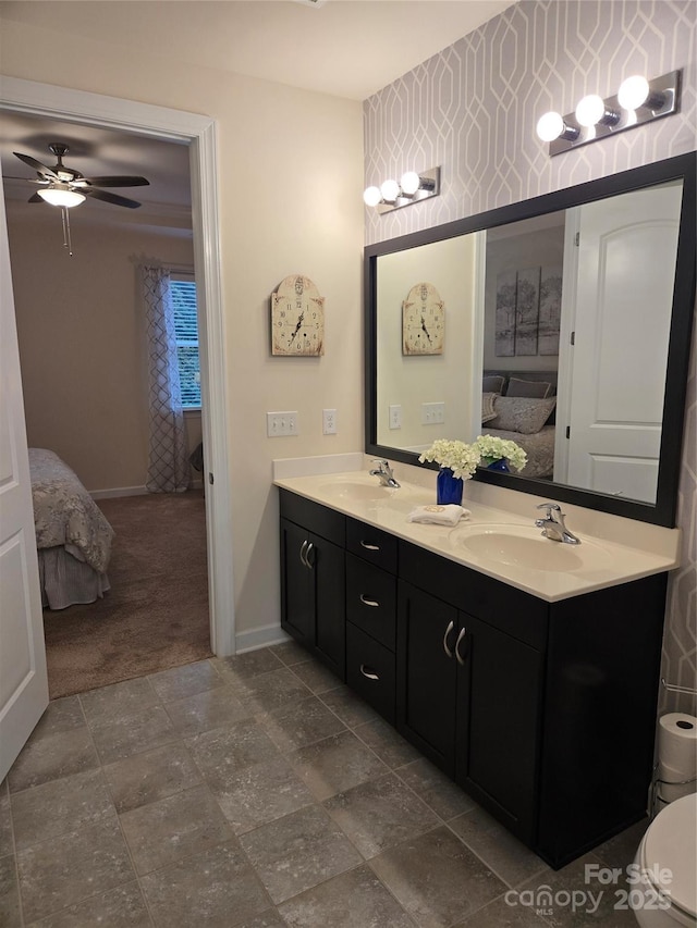 bathroom with double vanity, a sink, baseboards, and ensuite bathroom