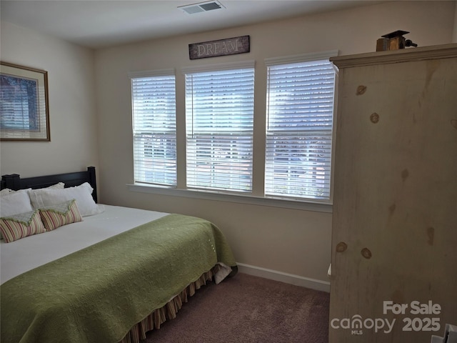 carpeted bedroom featuring visible vents, baseboards, and multiple windows