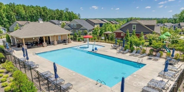 community pool featuring a patio area, a residential view, and fence