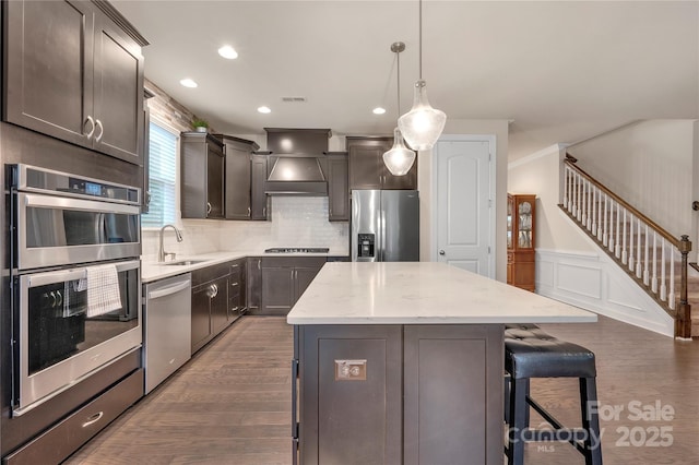 4929 Norman Park Pl, Clover, SC 29710 - kitchen featuring decorative backsplash, appliances with stainless steel finishes, premium range hood, a center island, and wood finished floors