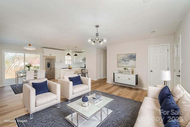 living room featuring light wood-type flooring and a notable chandelier