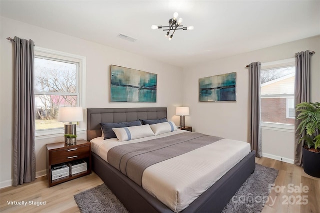 bedroom with a chandelier and light hardwood / wood-style flooring