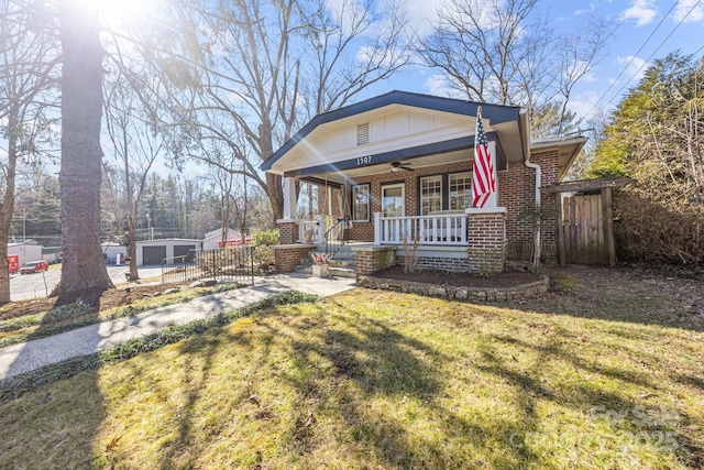 bungalow-style home with a garage, an outdoor structure, a front yard, and covered porch