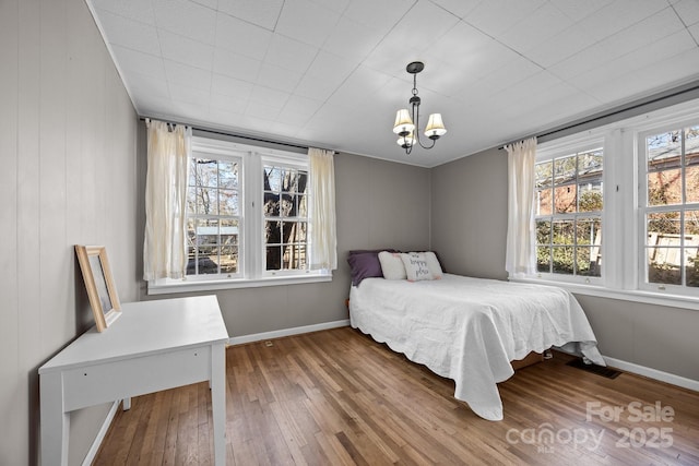 bedroom with an inviting chandelier and hardwood / wood-style flooring