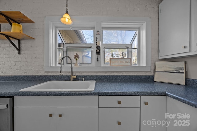 kitchen with dishwasher, white cabinetry, hanging light fixtures, and sink