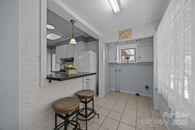 kitchen featuring light tile patterned floors, decorative light fixtures, ornamental molding, and white fridge