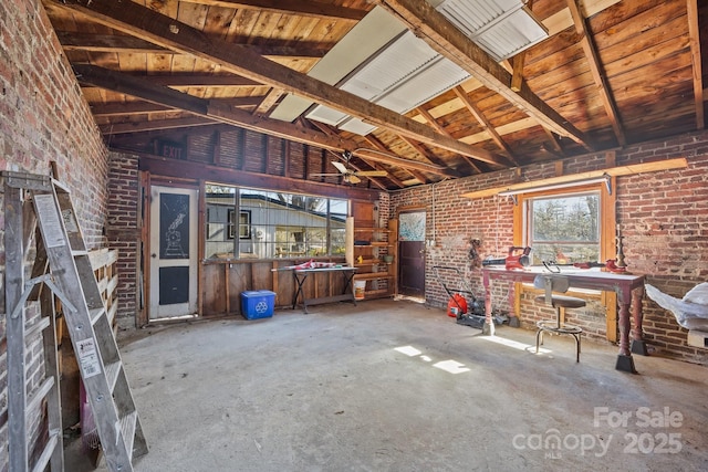 misc room featuring lofted ceiling and brick wall