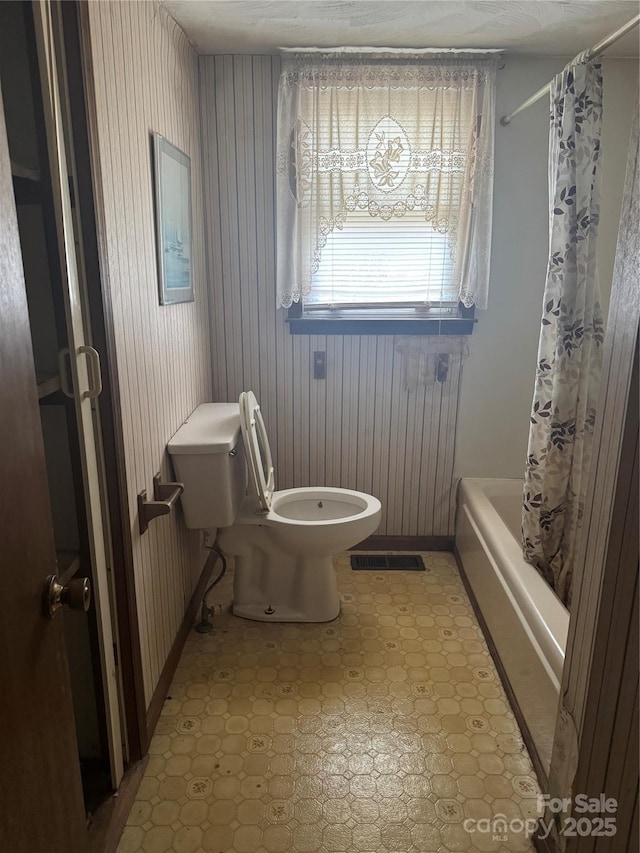 bathroom with shower / bath combination with curtain and toilet