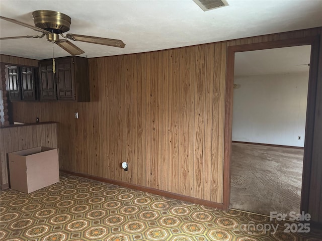 unfurnished room featuring wooden walls and ceiling fan