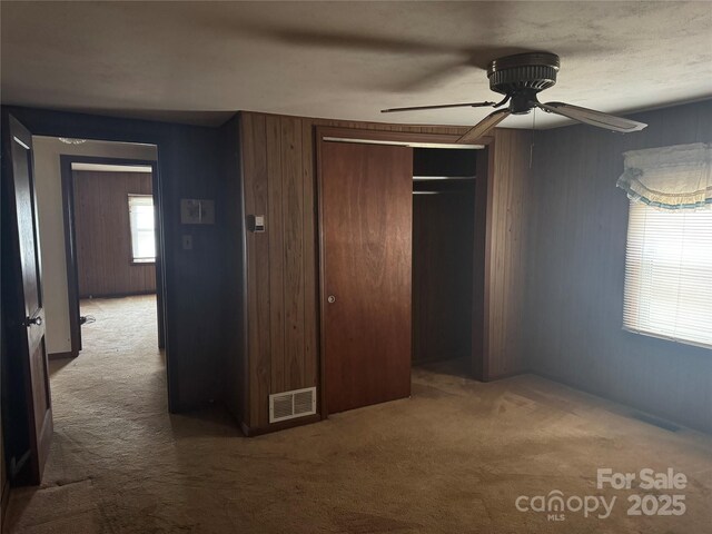 unfurnished bedroom with wooden walls, carpet flooring, and a closet