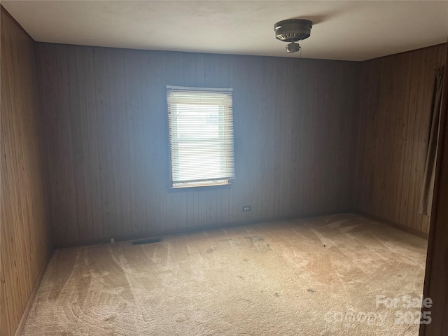 carpeted spare room featuring wood walls