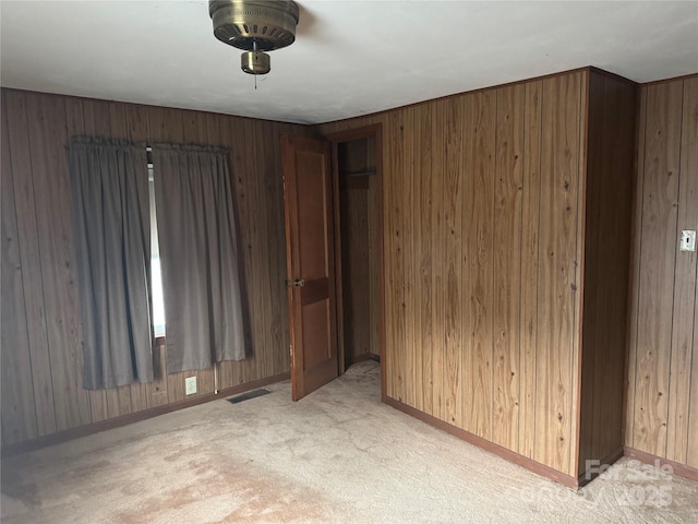 carpeted empty room featuring wood walls