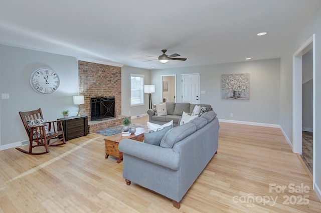 living room with ceiling fan, a fireplace, and light hardwood / wood-style floors