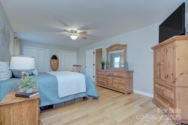 bedroom with ceiling fan, light hardwood / wood-style flooring, and multiple closets