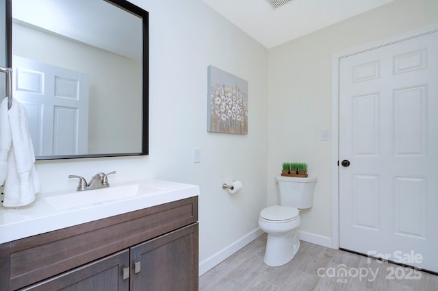 bathroom featuring vanity, hardwood / wood-style flooring, and toilet