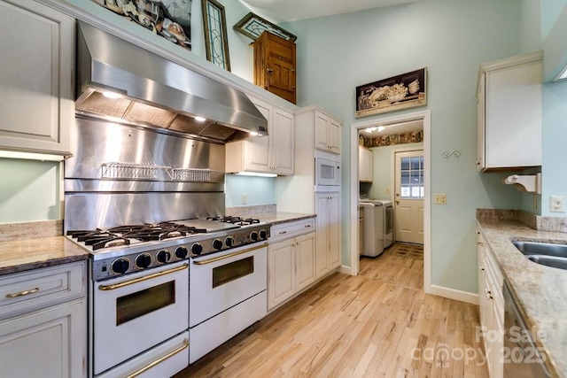 kitchen featuring light stone counters, washing machine and dryer, range with two ovens, and white cabinets