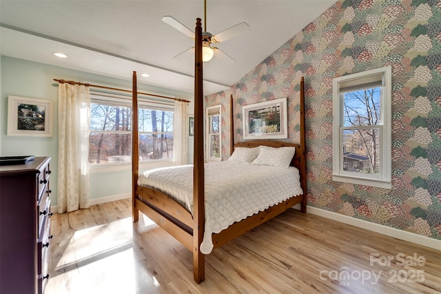 bedroom with ceiling fan, vaulted ceiling, and light wood-type flooring