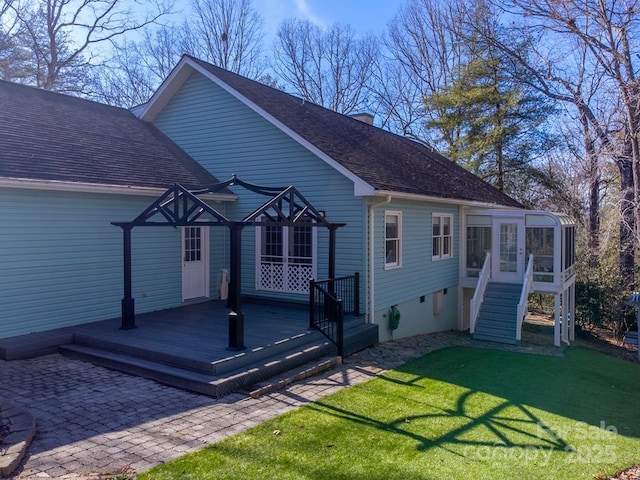 rear view of property featuring a wooden deck, a yard, and a sunroom