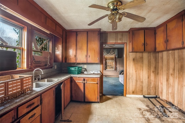 kitchen featuring ceiling fan, sink, a textured ceiling, and wood walls