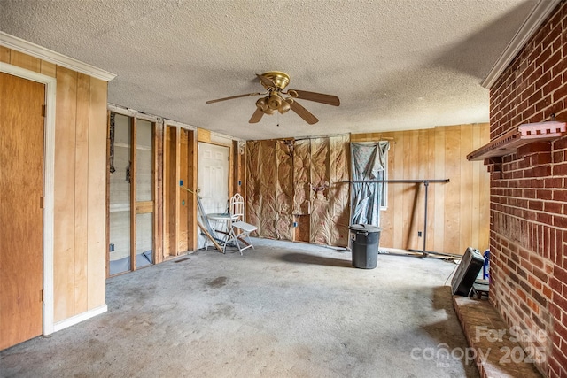 miscellaneous room featuring ceiling fan, a textured ceiling, and wood walls