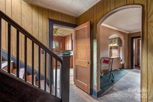 interior space with crown molding, wood-type flooring, wooden walls, and a textured ceiling