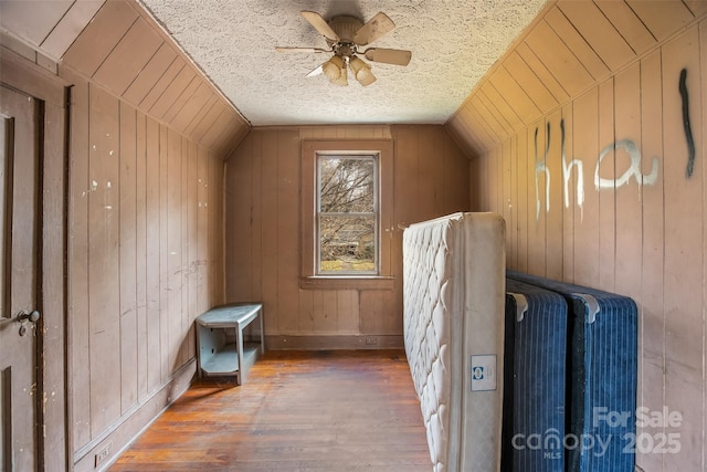 bonus room with dark wood-type flooring, lofted ceiling, and wood walls