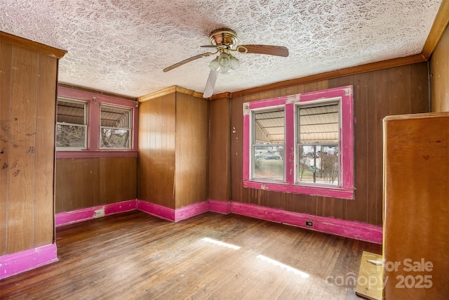 spare room with ceiling fan, wood-type flooring, a textured ceiling, and wood walls