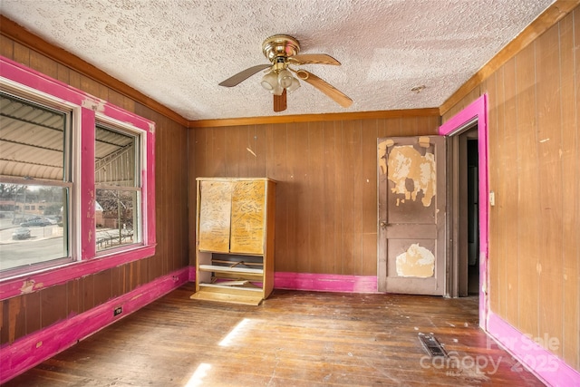 spare room with wood-type flooring, ceiling fan, a textured ceiling, and wooden walls