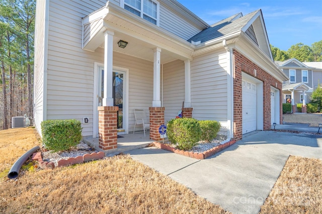 property entrance with a garage, central air condition unit, and covered porch