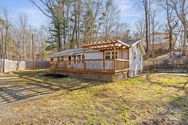 rear view of house with a wooden deck, a pergola, and a lawn