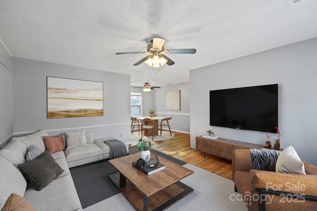 living room with hardwood / wood-style flooring, ceiling fan, and a textured ceiling