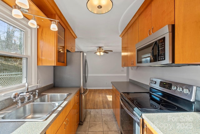 kitchen featuring stainless steel appliances, sink, light tile patterned floors, and ceiling fan